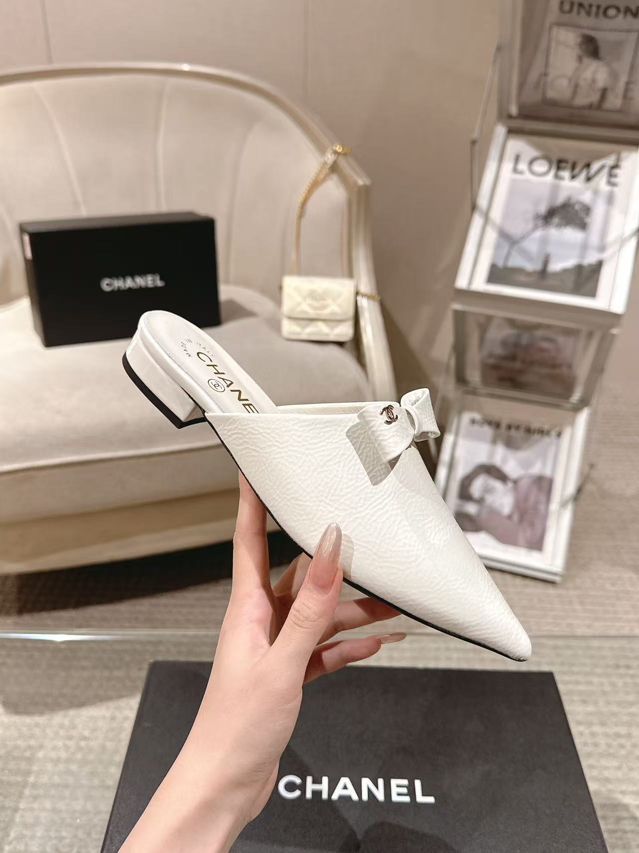White Chanel flats with bow strap and slim low heel, angled view