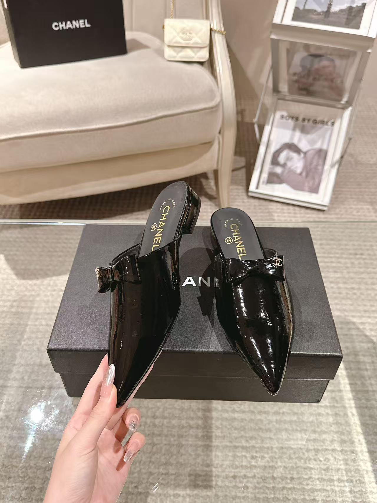 Women’s black patent pointed-toe mules with small bow detail near the strap