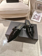 Women’s pair of glossy black patent pointed-toe mules with CHANEL branding