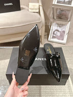 Women’s black patent pointed-toe mules with decorative insole detail and CHANEL logo