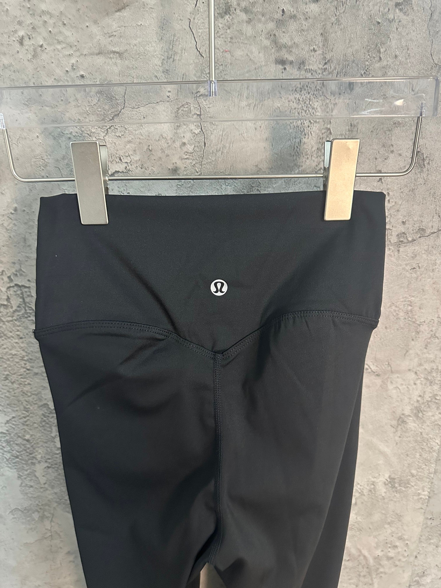 Black pants with small logo on front and V-shaped waistband seam.