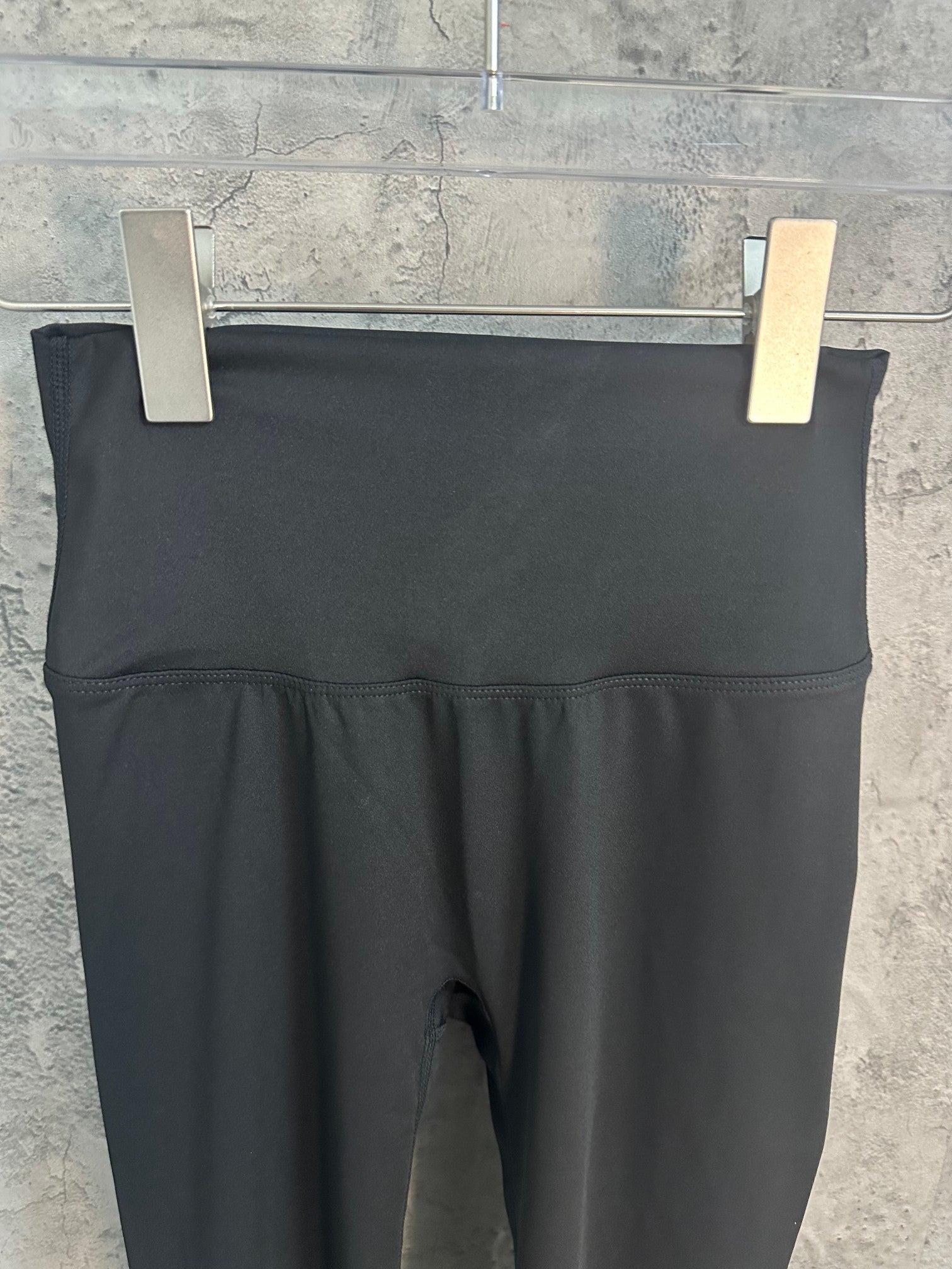 Black cropped pants with wide waistband and inner fly seam visible.
