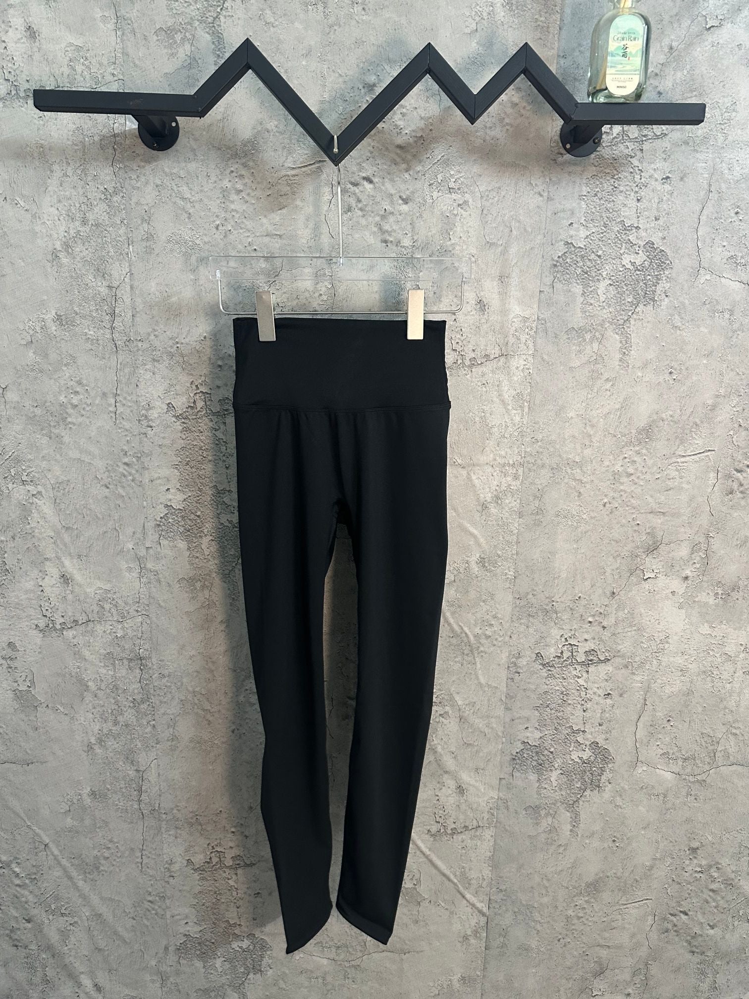 Black pants with tapered legs and waistband, hung on clips.