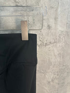 Black pants side view with smooth waistband and stitched hem.