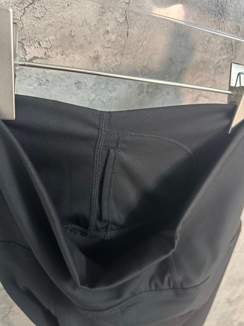 Black pants close-up showing waistband seam and interior pocket stitching.