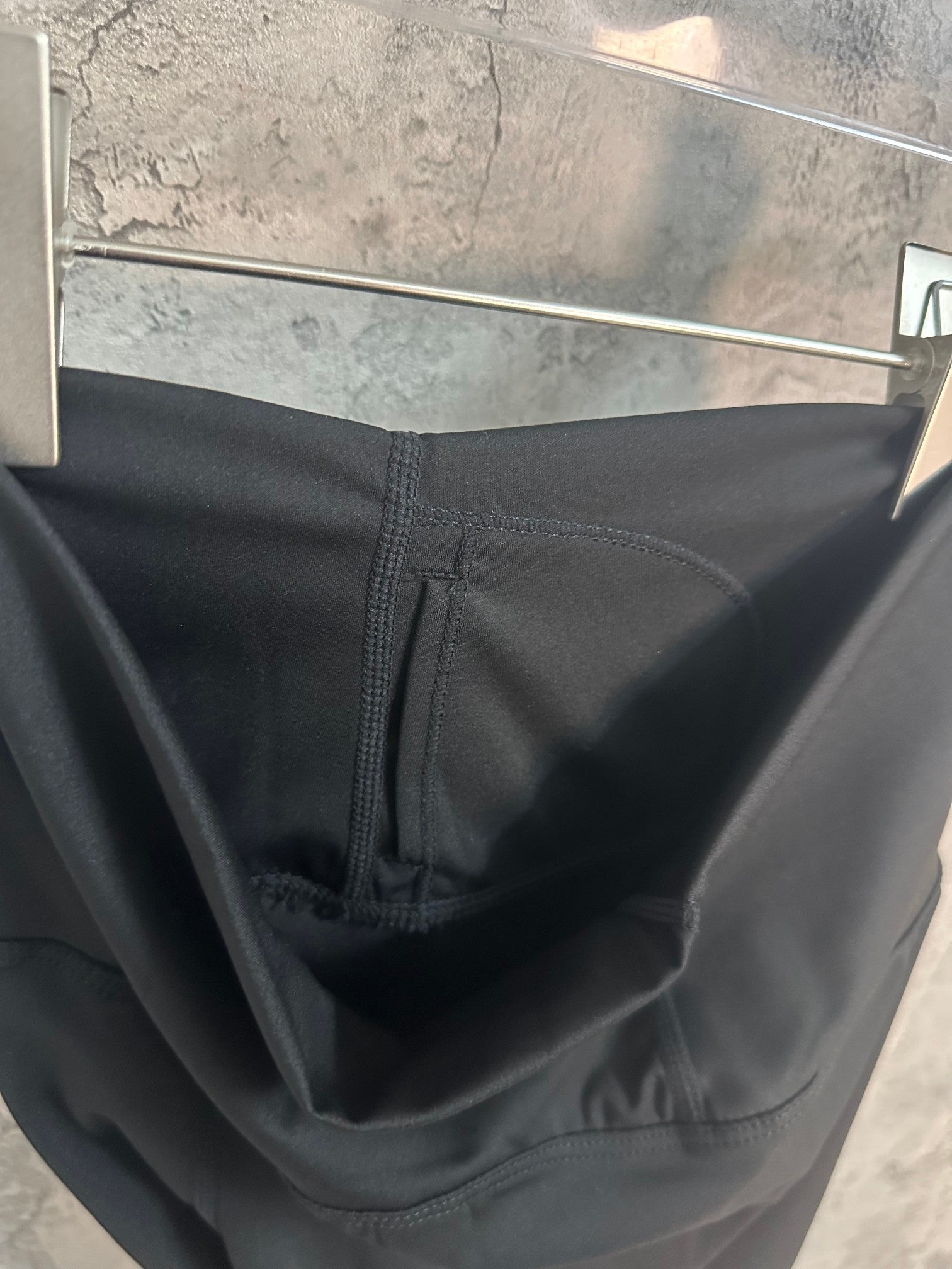 Black pants close-up showing waistband seam and interior pocket stitching.