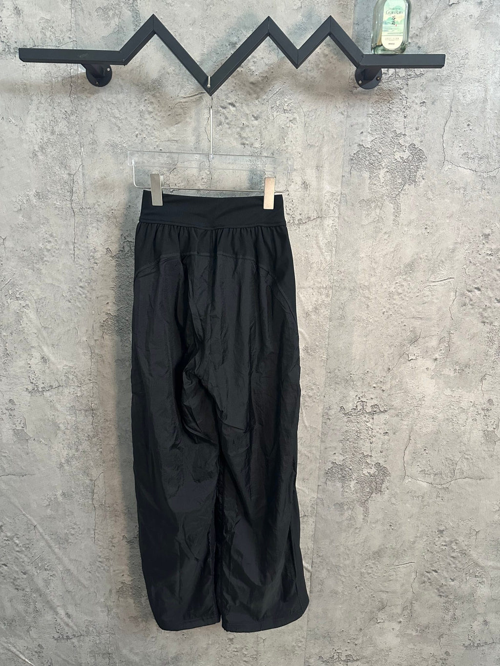 Dark wide-leg pants on hanger, elastic waistband and front pleats