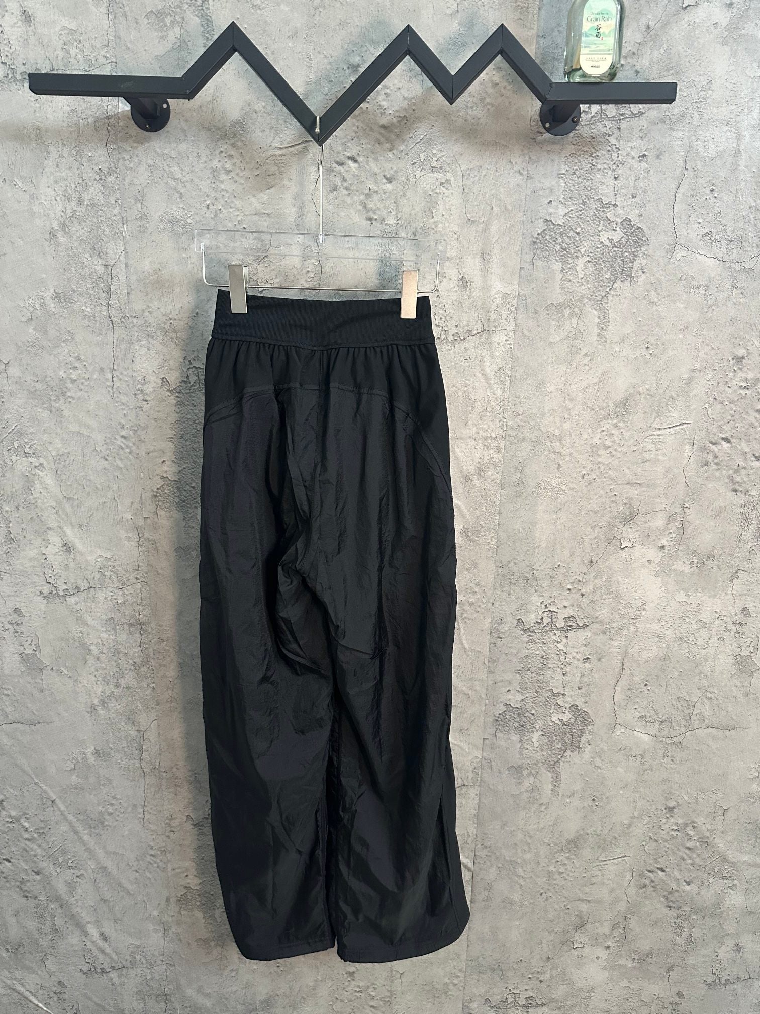 Dark wide-leg pants on hanger, elastic waistband and front pleats