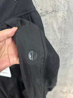 Dark pants with snap button closure and small circular logo patch