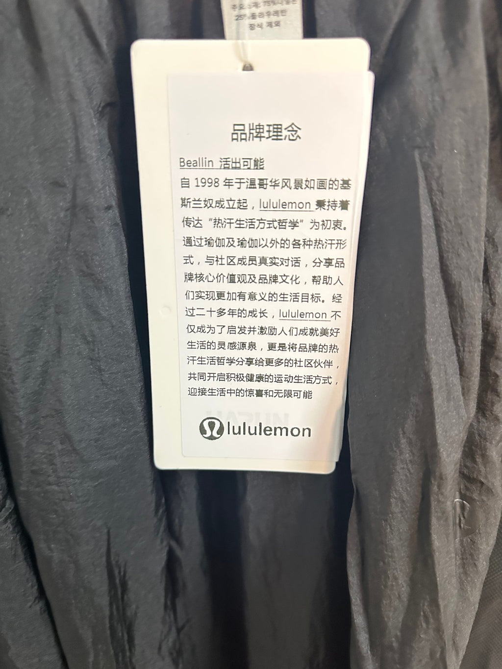 Clothing hang tag attached to dark pants, with brand and product info