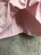 Pink T-shirt hem with stitched seam and partial printed letters