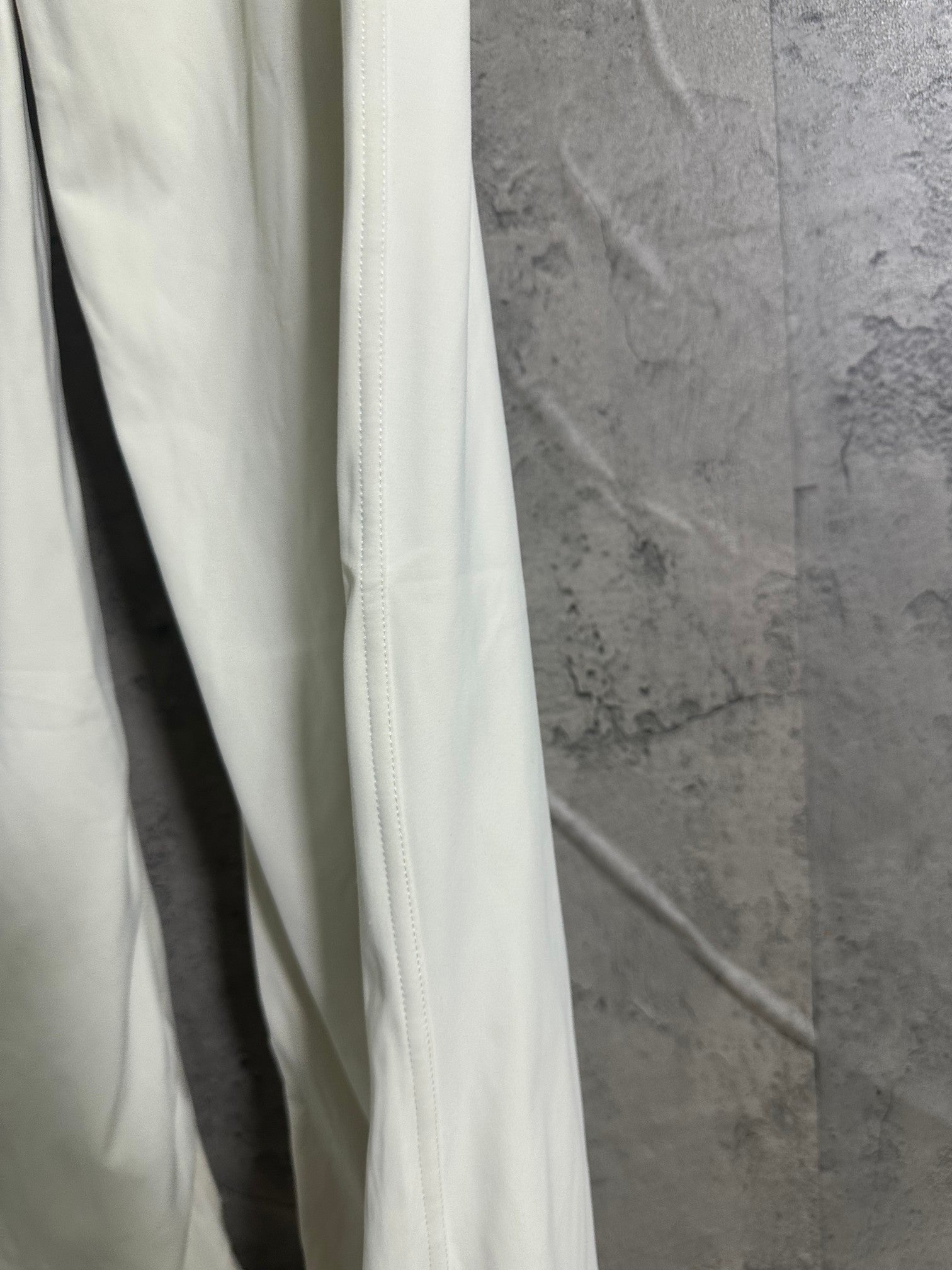 White pants leg with vertical seam and stitched cuff edge
