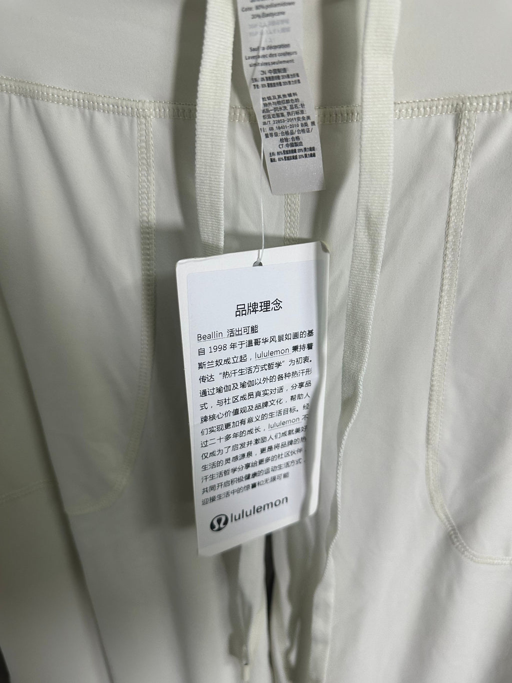 White pants with size and care tags attached near waistband.