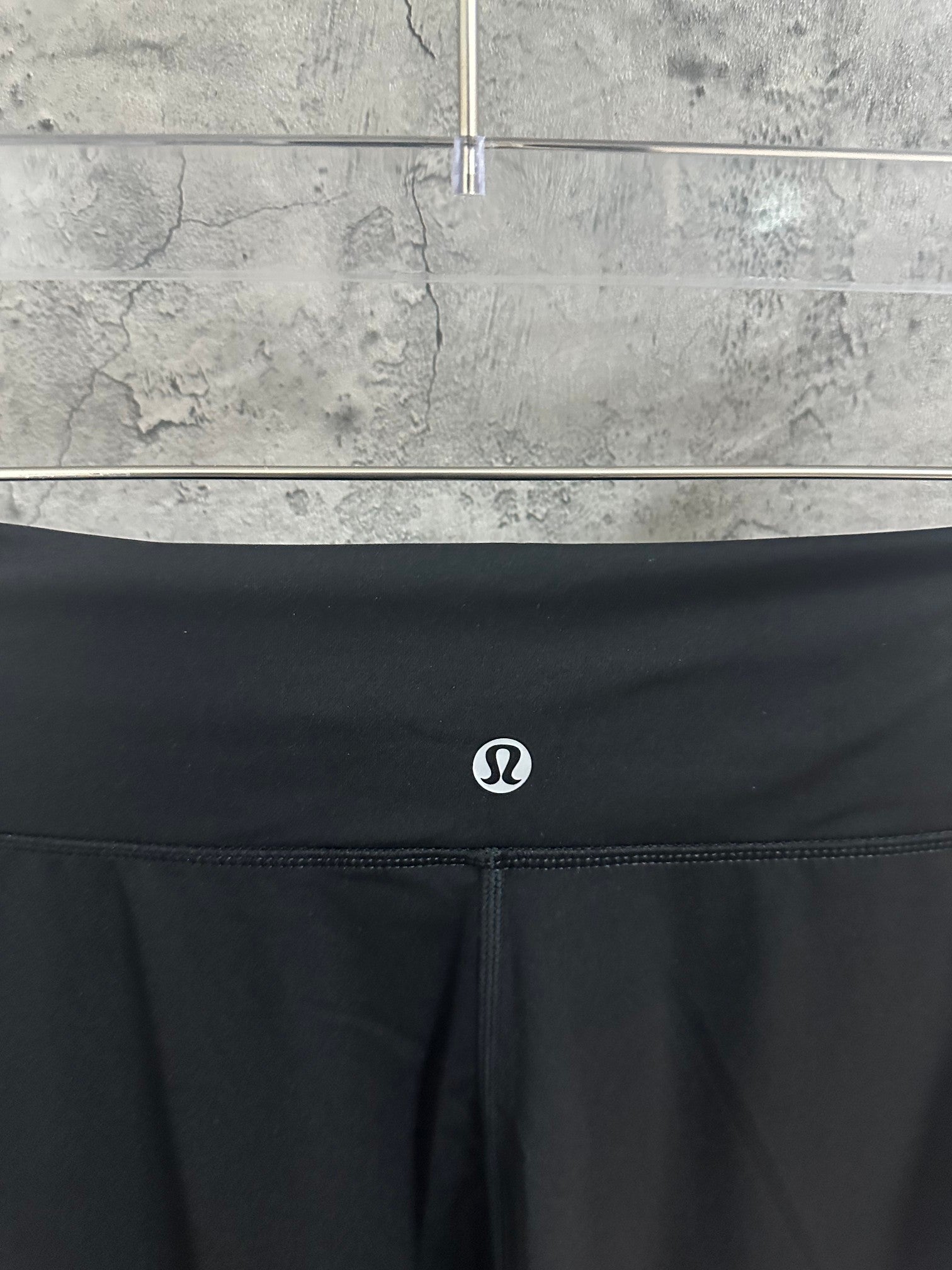Dark elastic-waist pants with small circular logo at center front