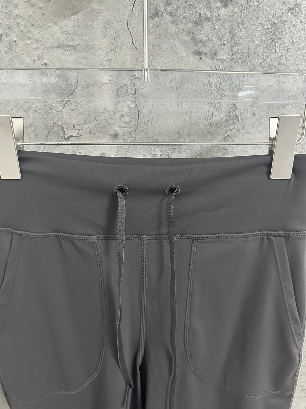 Dark gray jogger-style pants waistband with drawstring and stitched panel