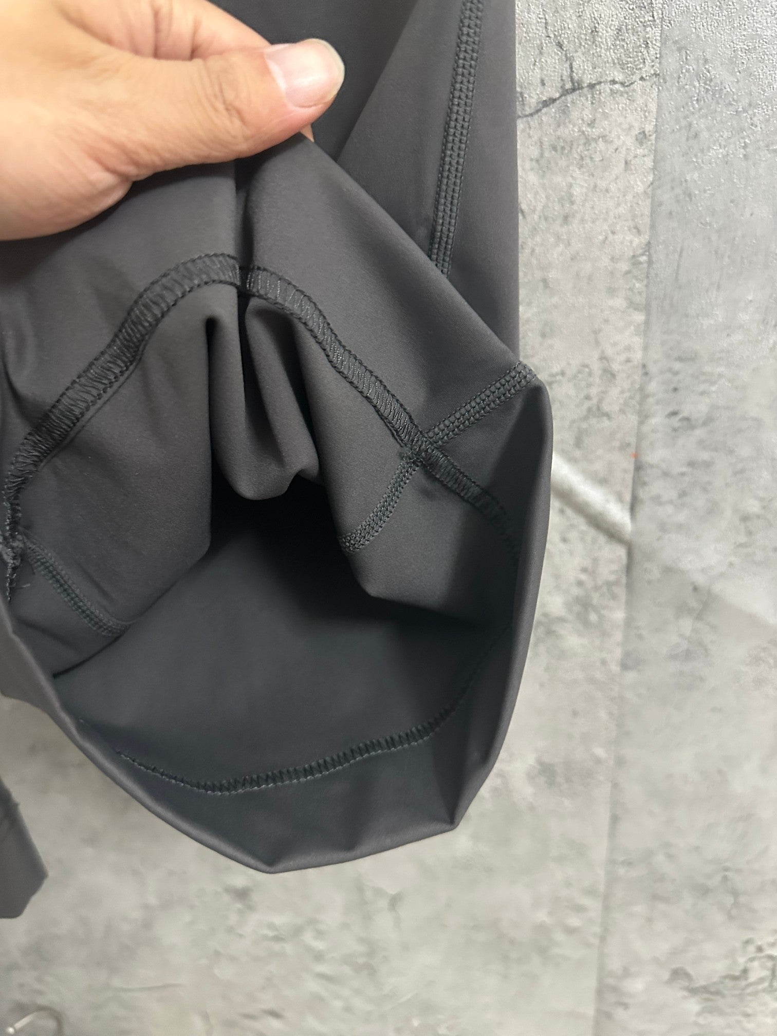 Dark gray drawstring pocket area with curved seam and stitching