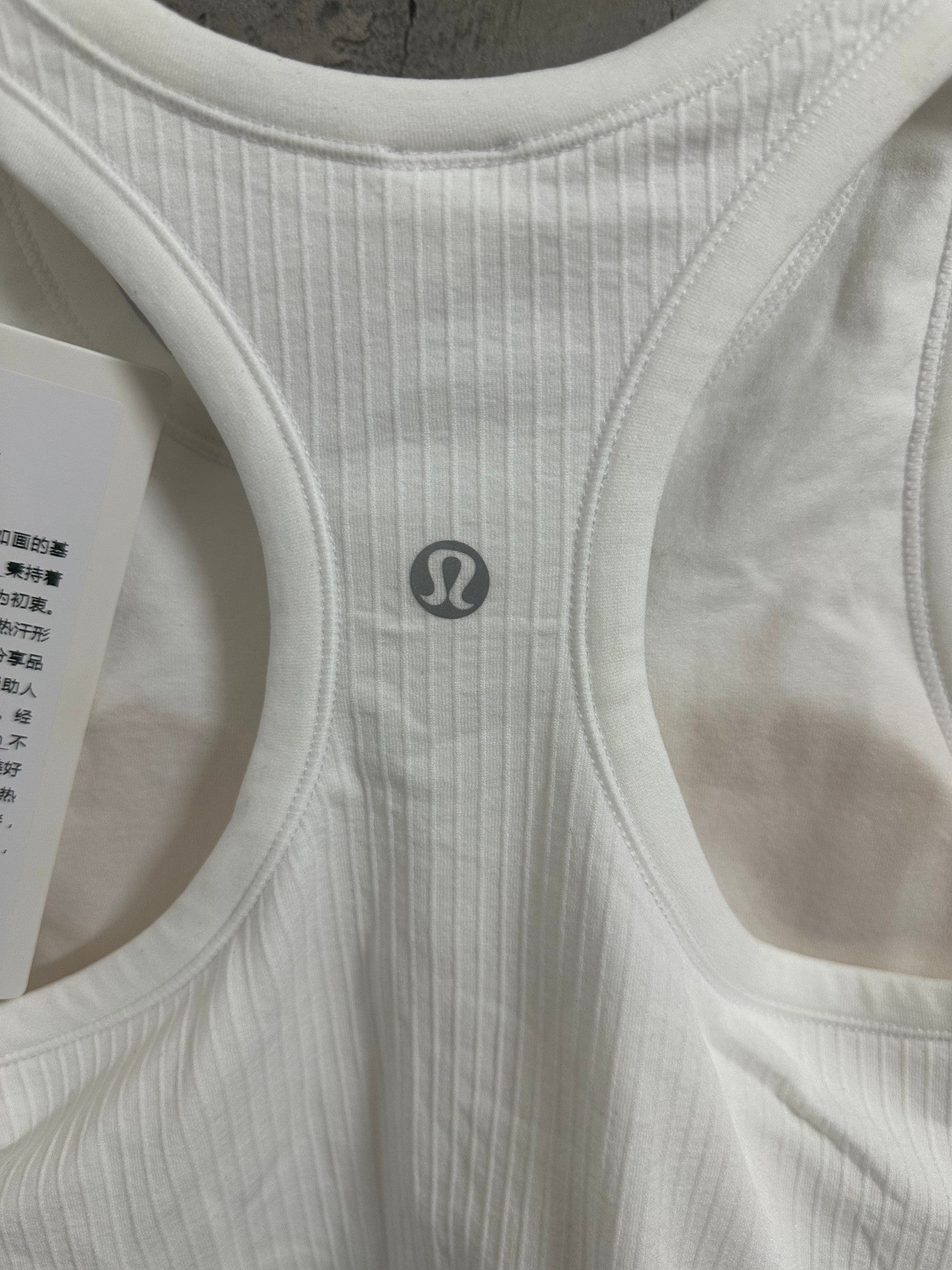 White ribbed tank top with small circular chest logo