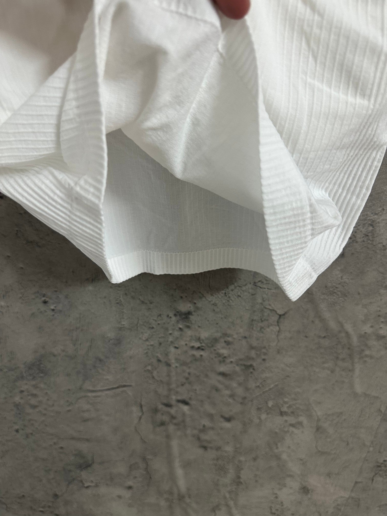 White ribbed tank top with flared hem and draped fabric