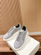 Grey suede low-top sneakers with lace-up closure and thick white platform sole