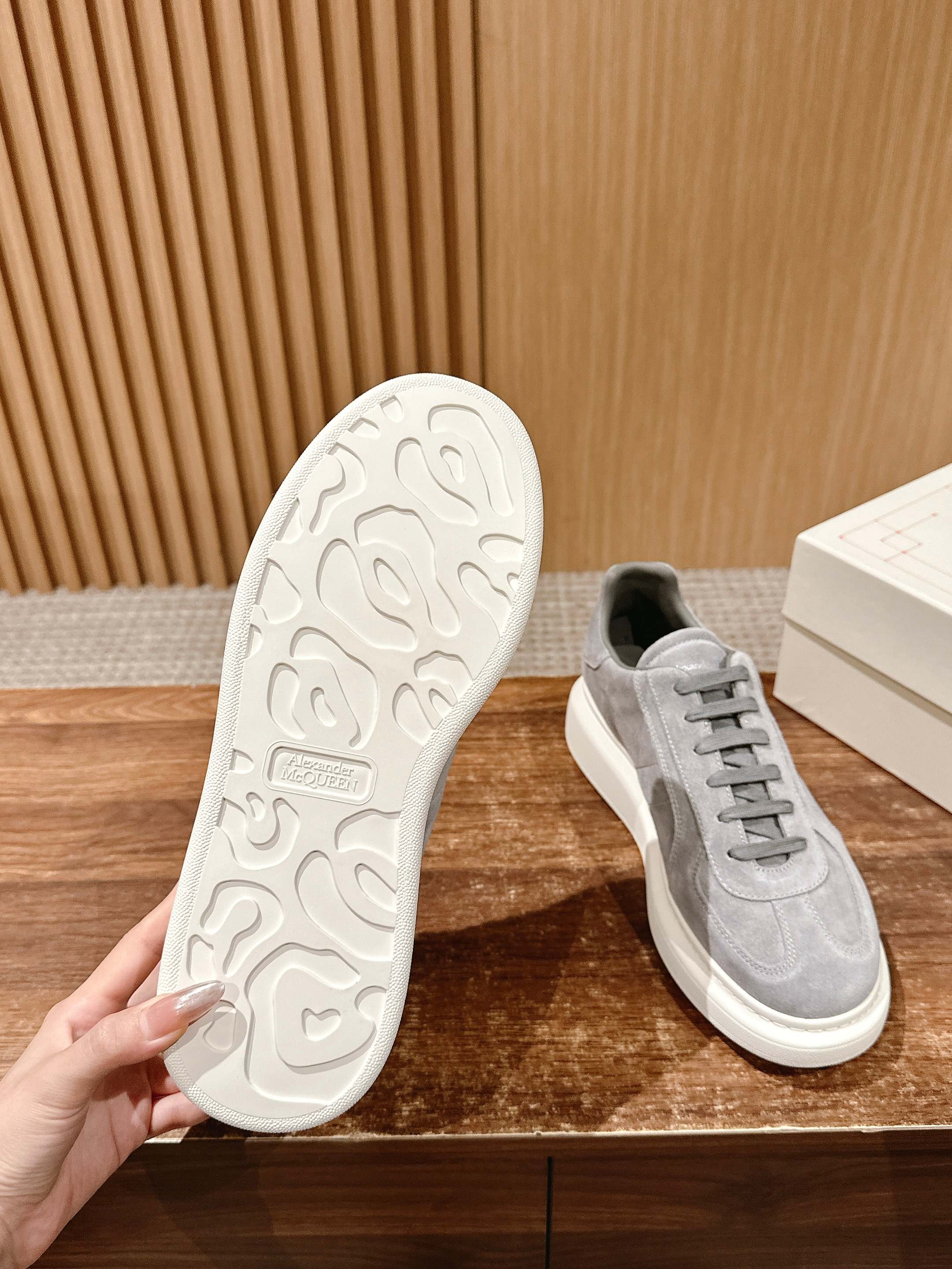Grey suede low-top sneakers showing textured white outsole and lace-up upper
