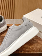 Alexander McQueen suede sneaker side view, light gray with stitched panel and white sole
