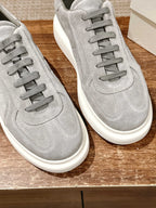 Grey suede low-top sneakers close-up, lace-up front with white rubber soles