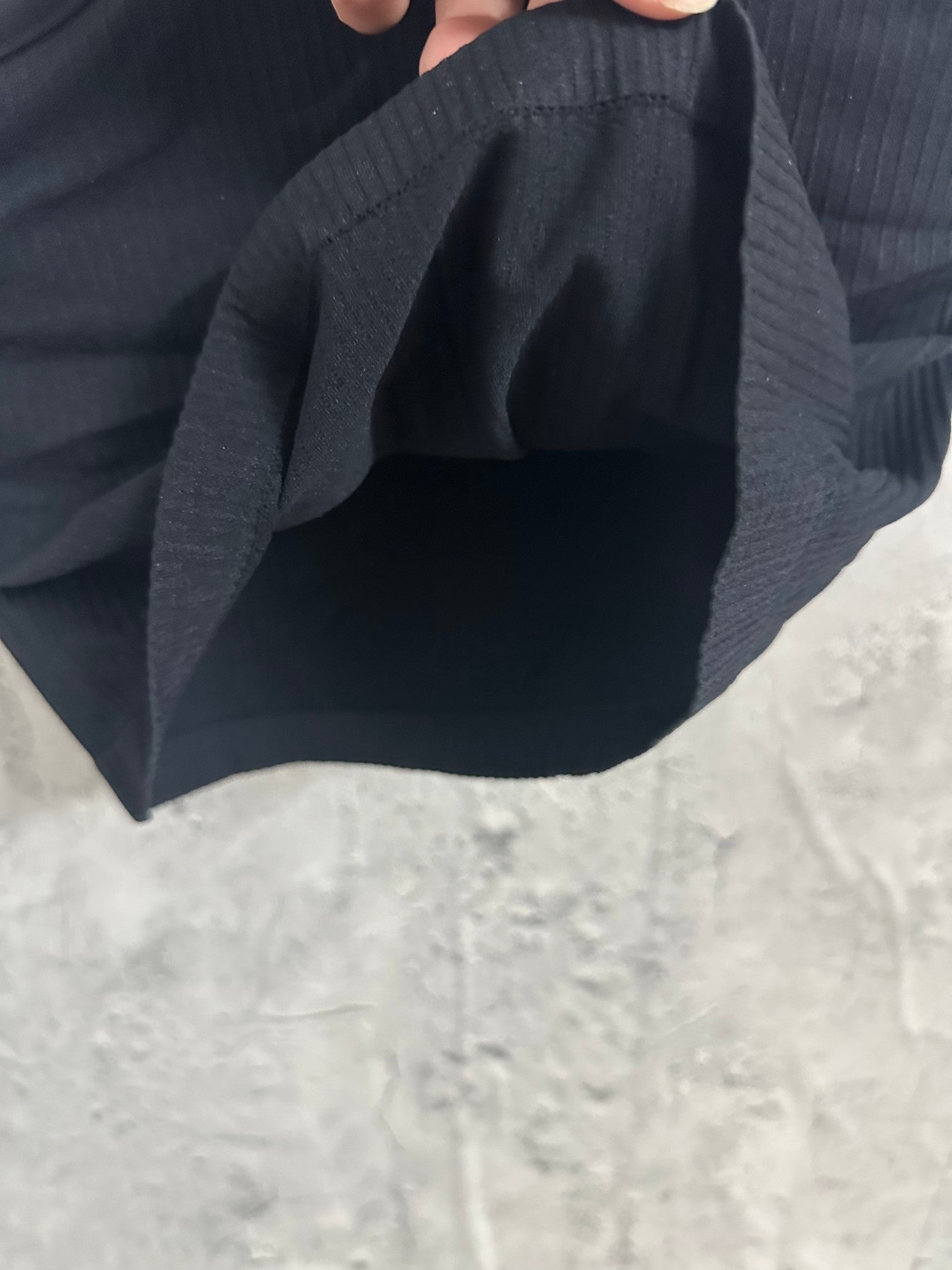 Black ribbed tank top fabric gathered in hand, showing texture