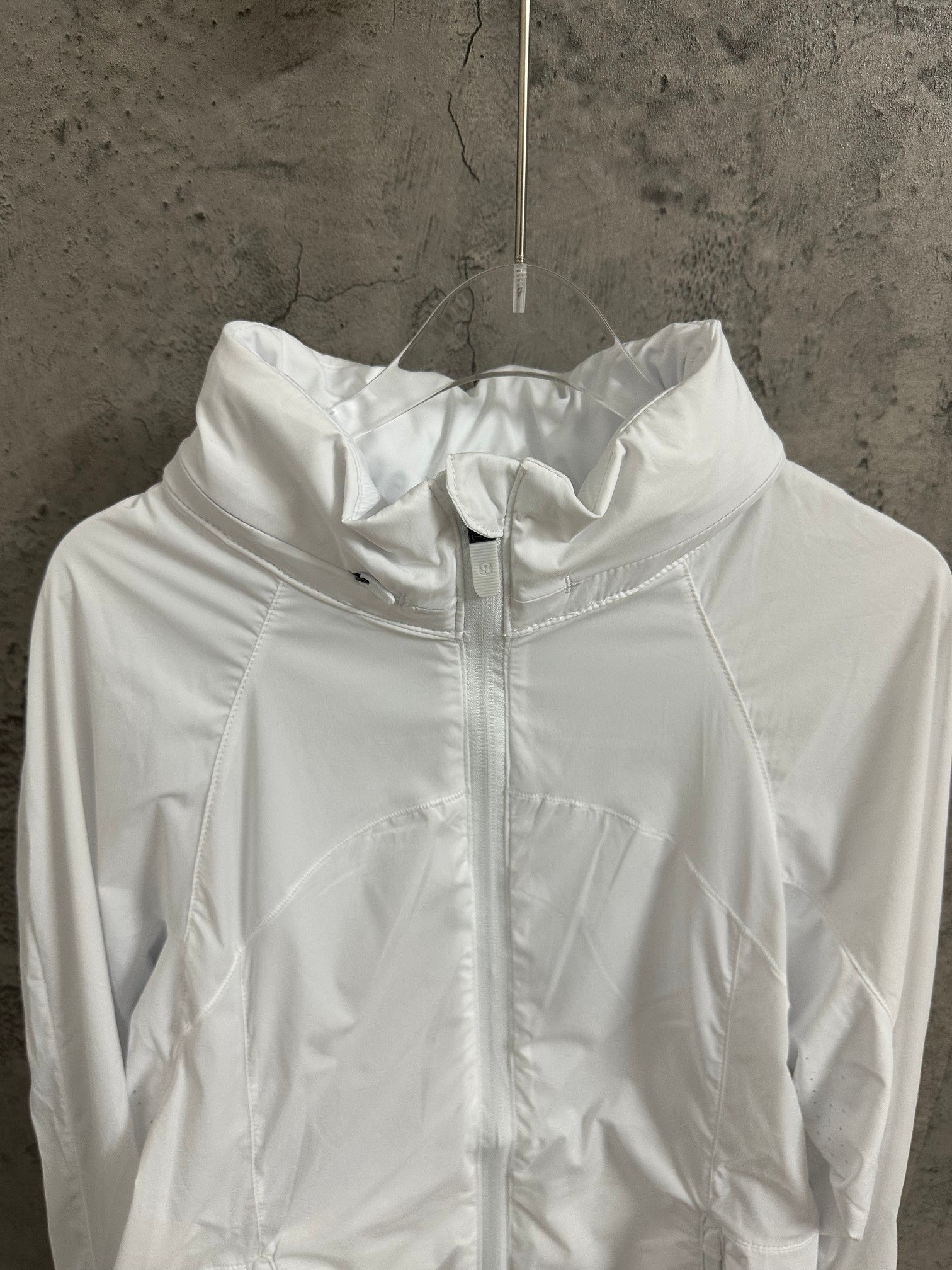 White hooded zip jacket close-up of hood and front zipper