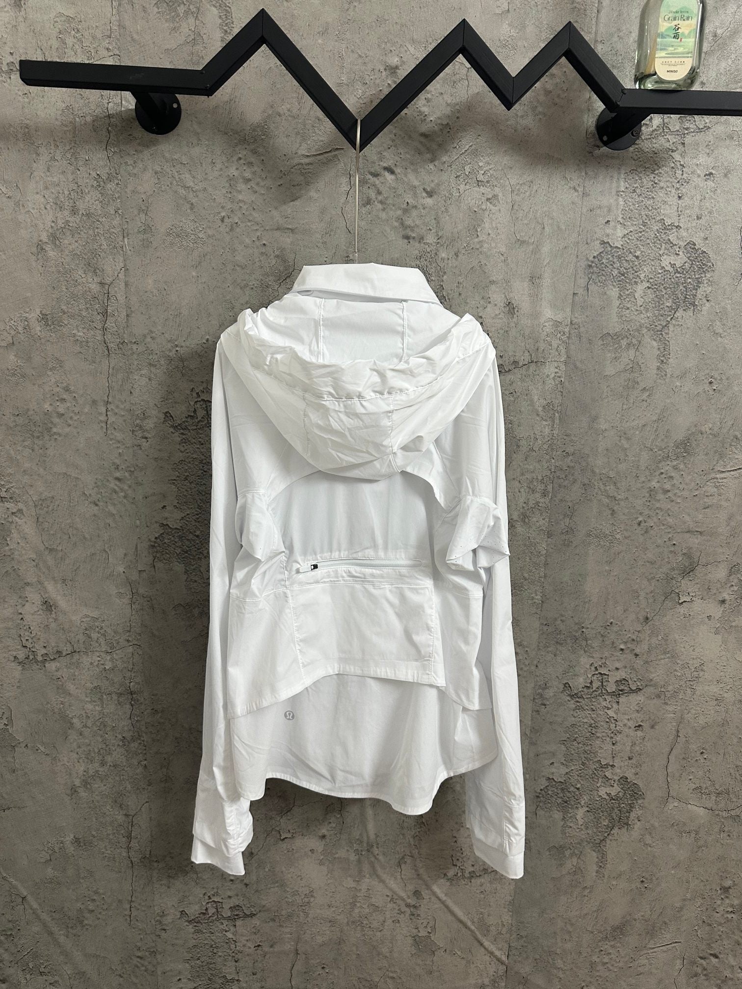 White hooded zip jacket, back view with gathered hood and wide hem