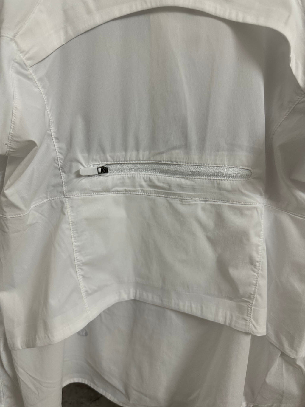 White jacket chest pocket with zipper and stitched panel detail