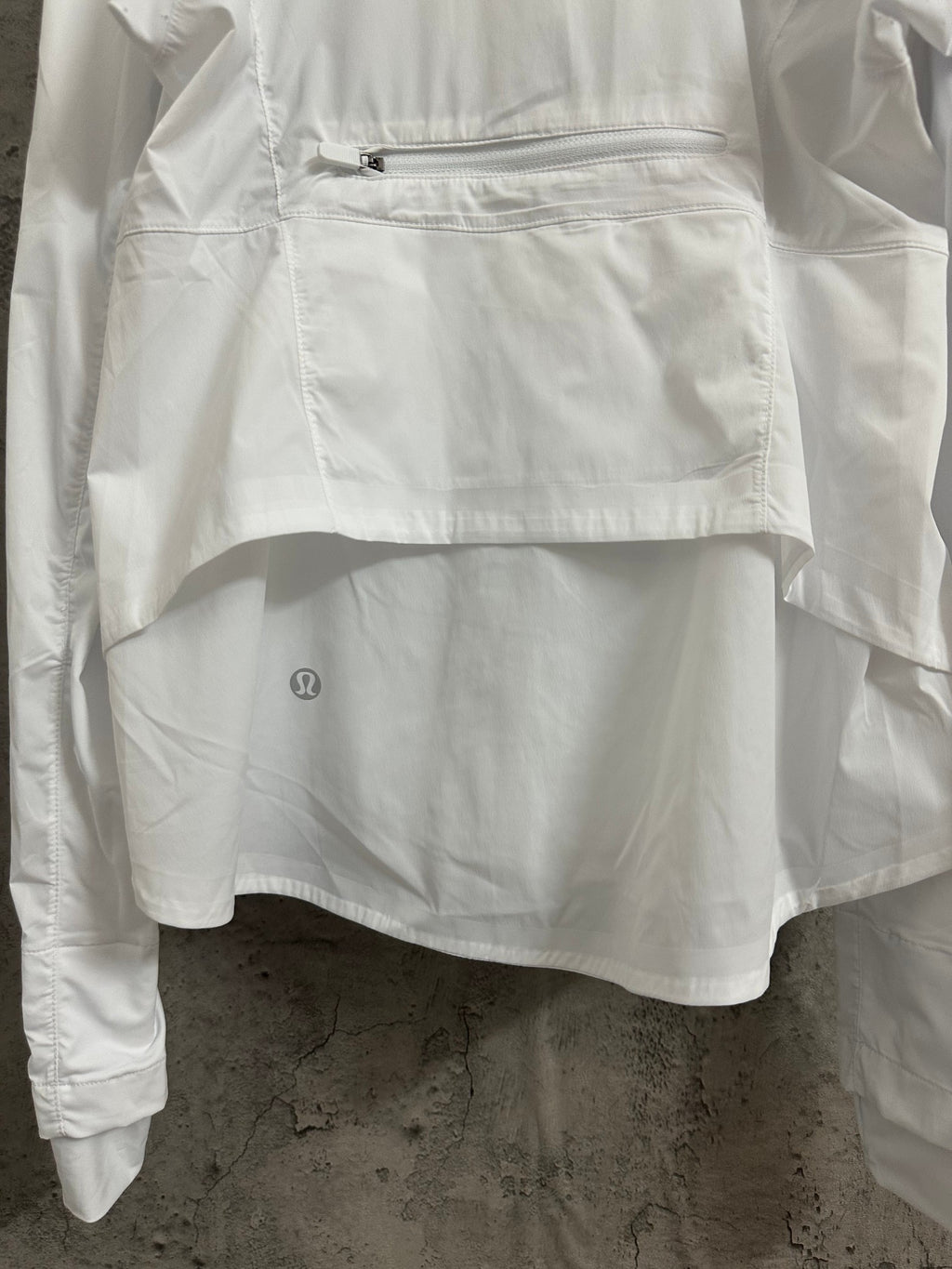 White jacket front with zipped pocket and small embroidered logo on hem