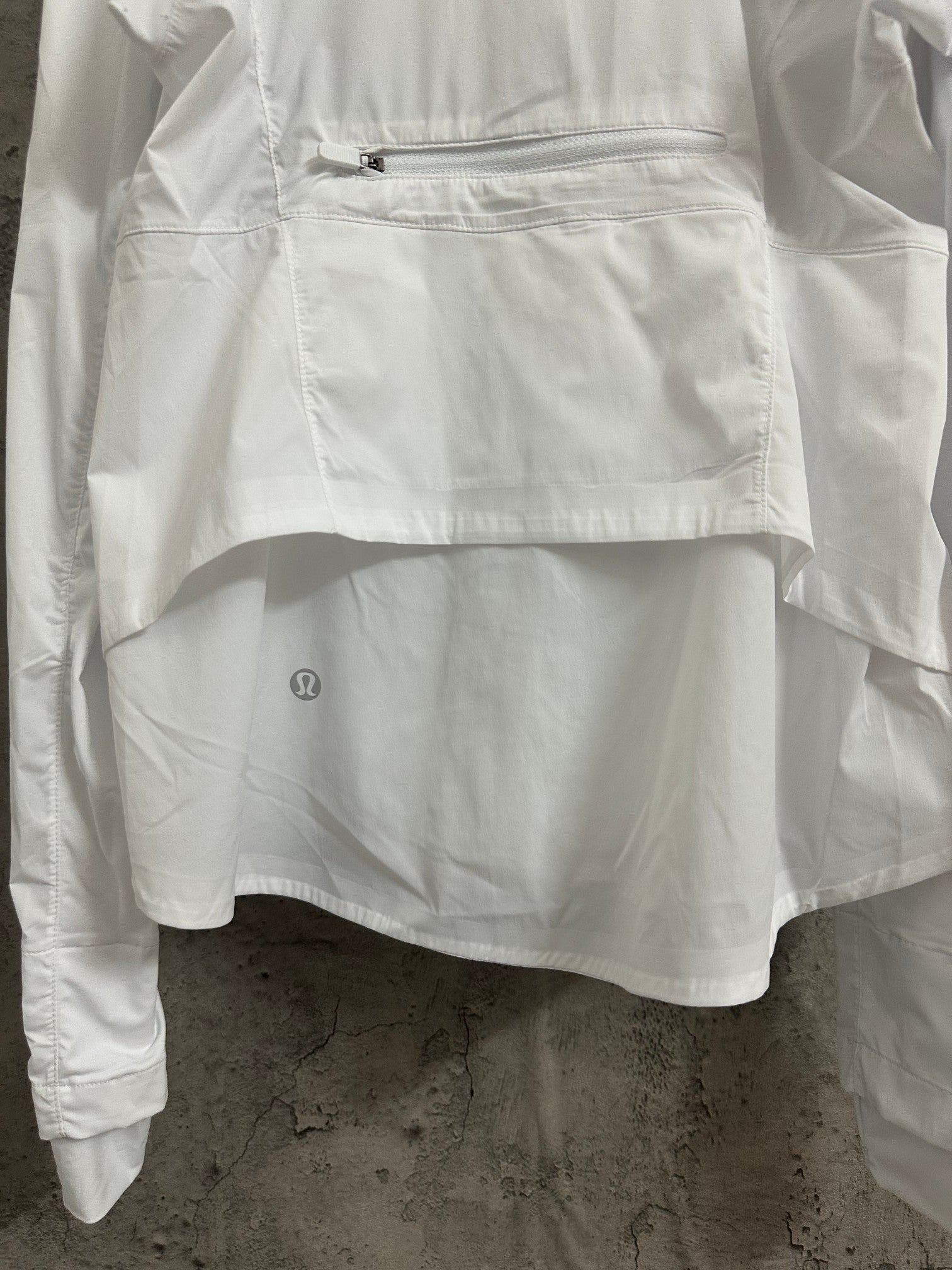 White jacket front with zipped pocket and small embroidered logo on hem