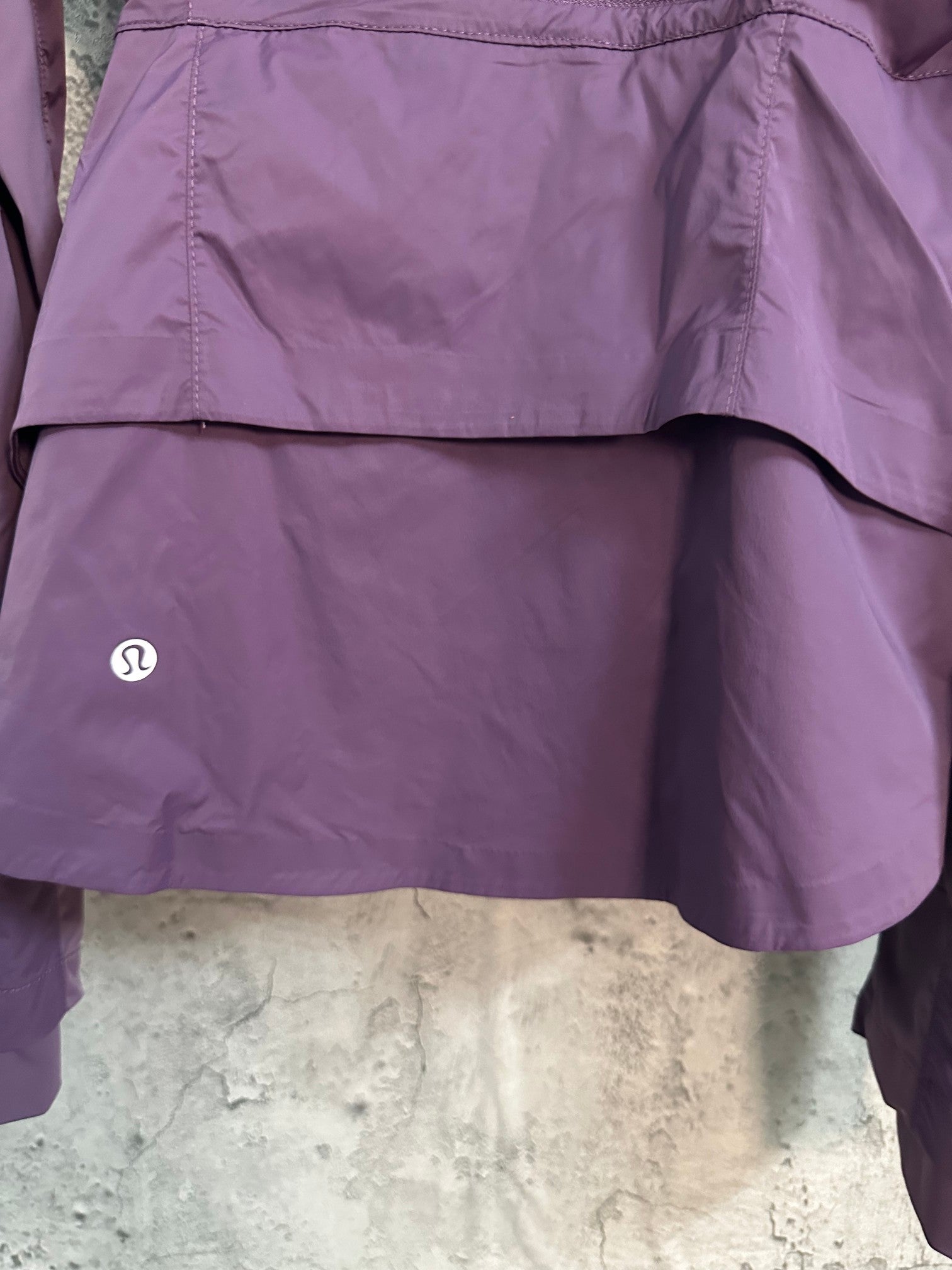 Purple windbreaker jacket hem with small logo badge