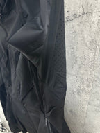 Hooded rain jacket sleeve and shoulder close-up with small ventilation holes, dark color