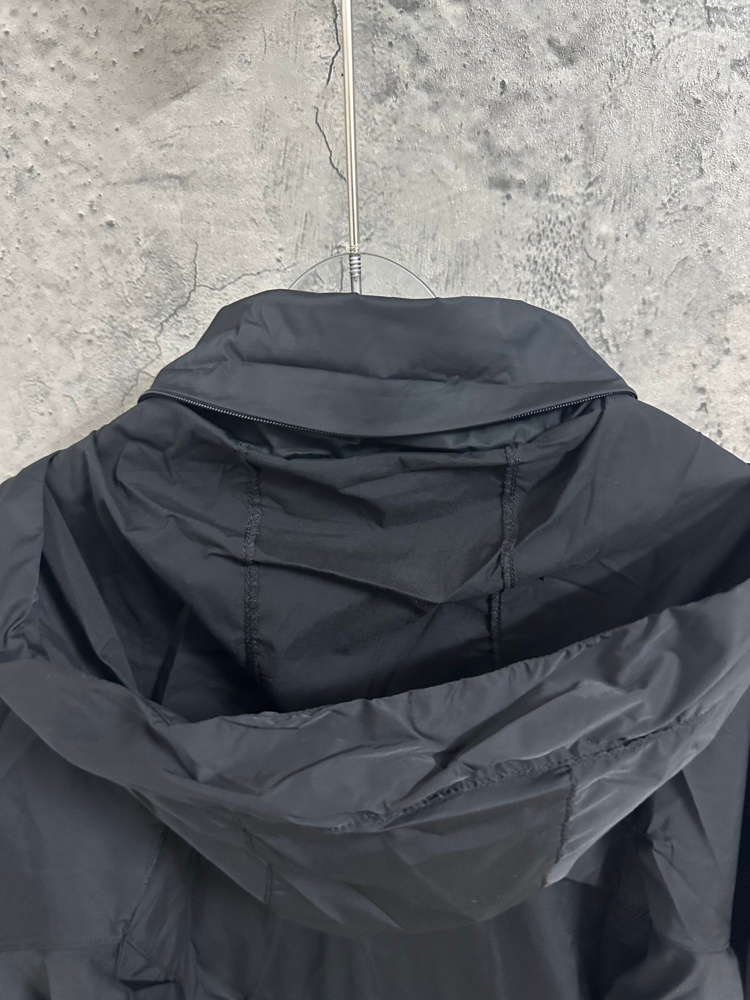 Hooded rain jacket hood close-up with layered collar, dark color