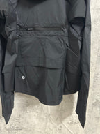 Hooded rain jacket back panel close-up with patch pocket and zipper accents, dark color