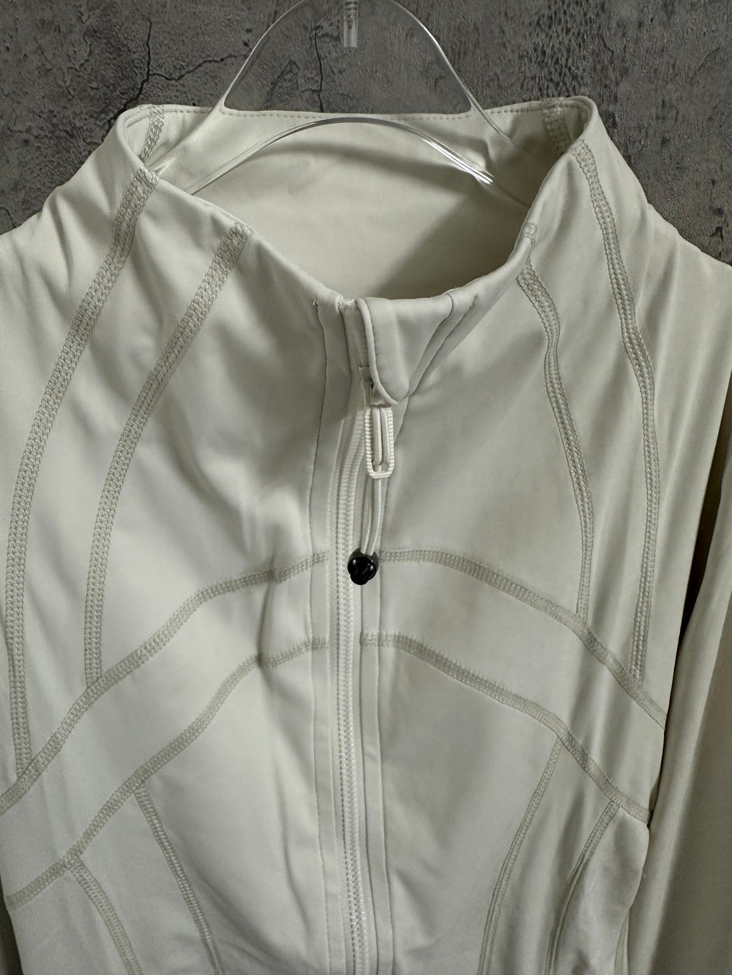 White jacket close-up with front zipper, stand collar, and stitched seam panels