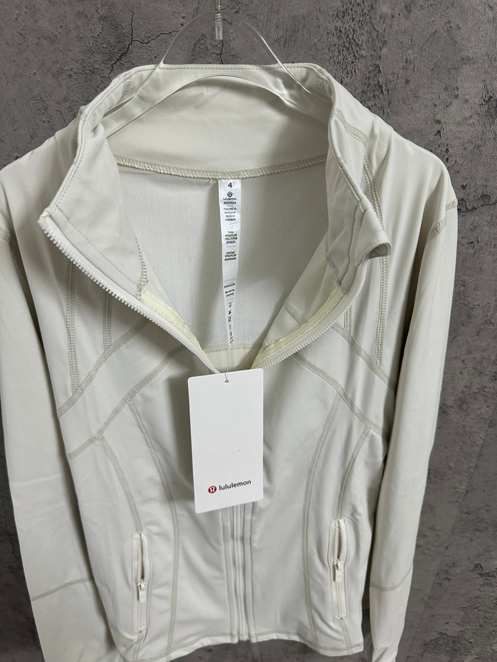 White zip jacket with stand collar, zip pockets, and size tag
