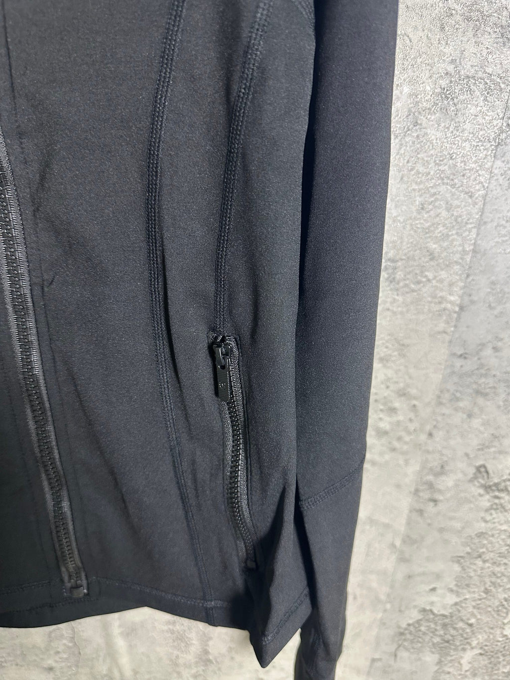 Black jacket side pocket opening with zipper closure along the seam