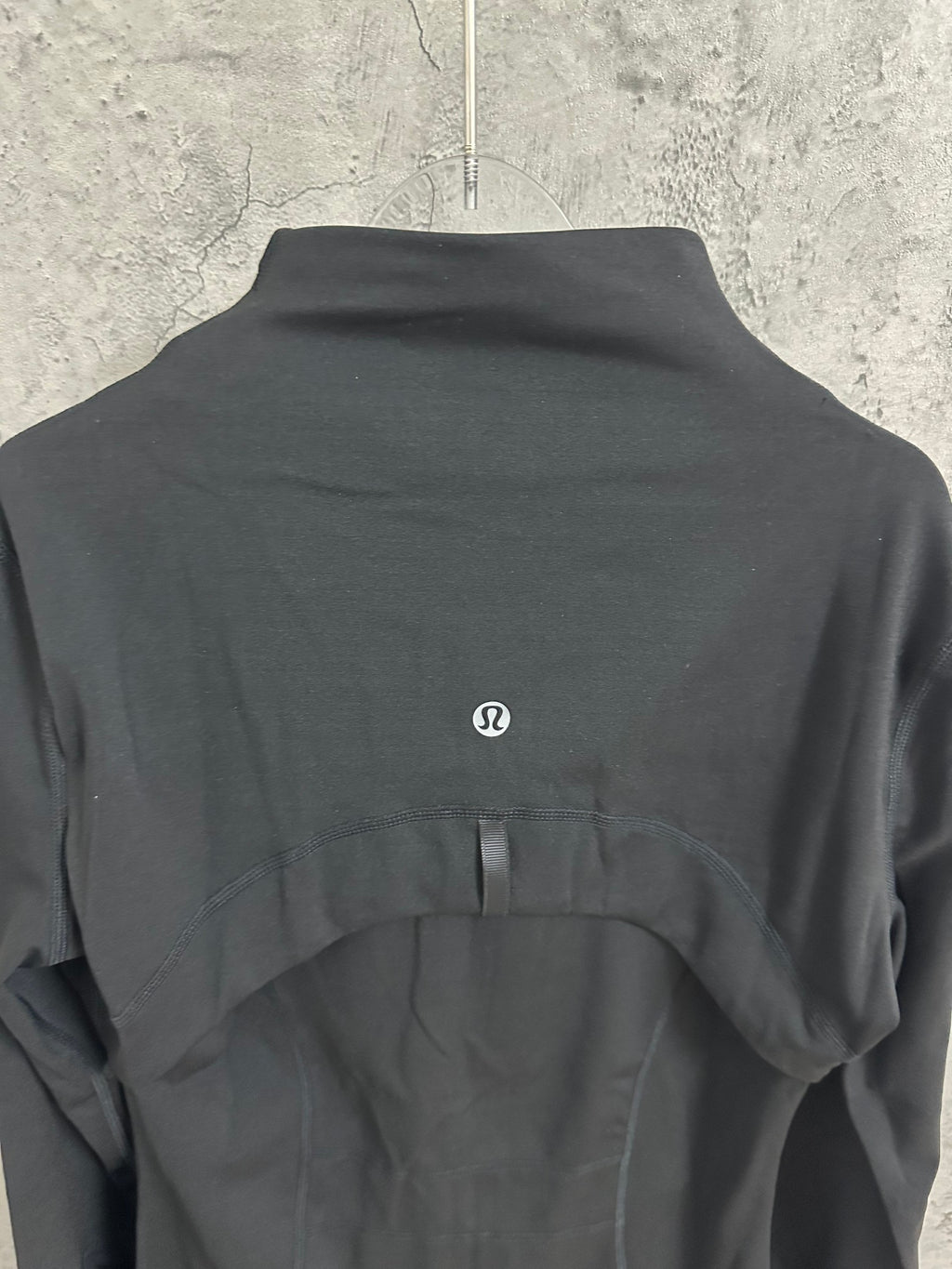 Black jacket back with small embroidered oval logo at upper center