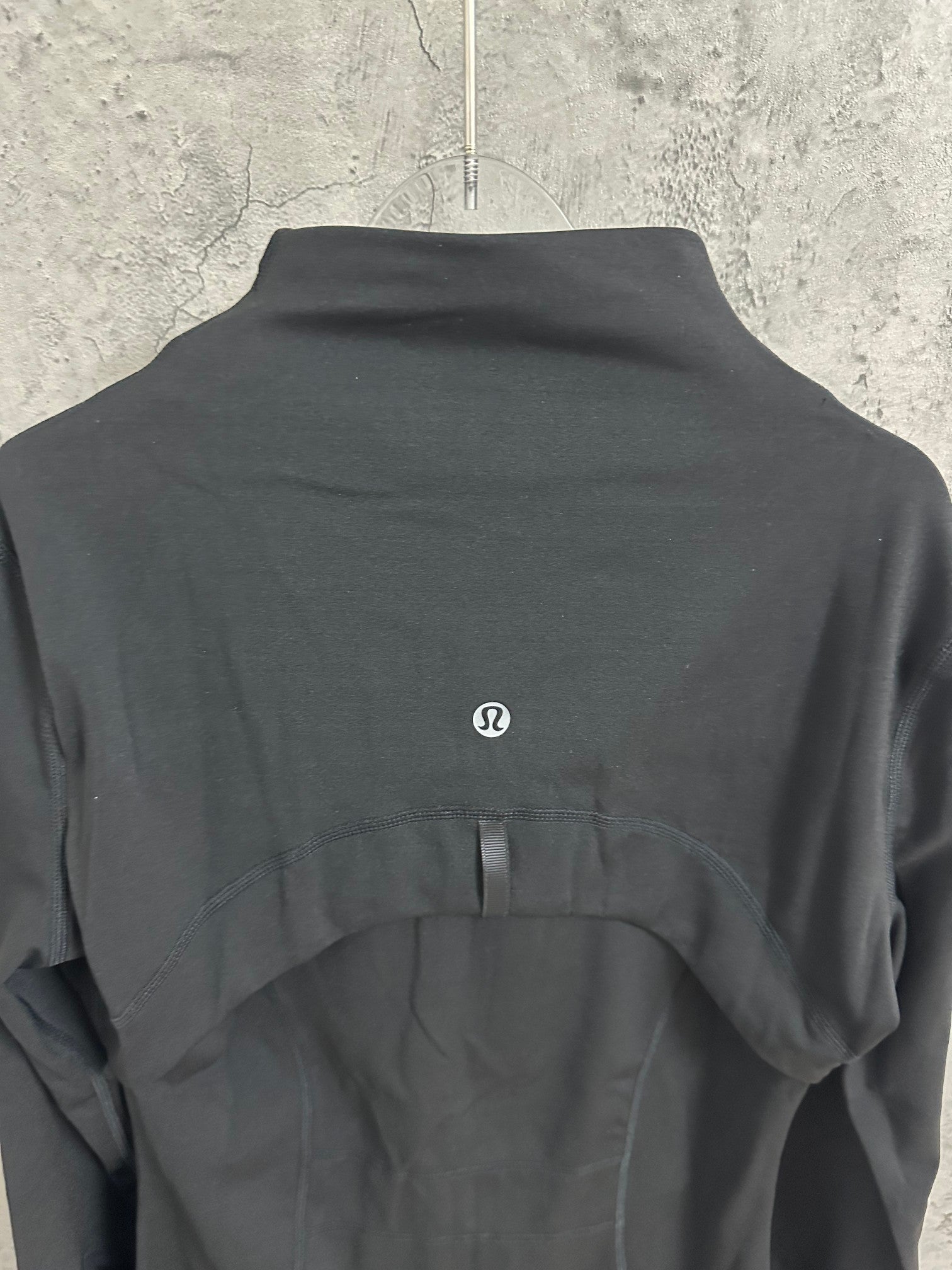 Black jacket back with small embroidered oval logo at upper center