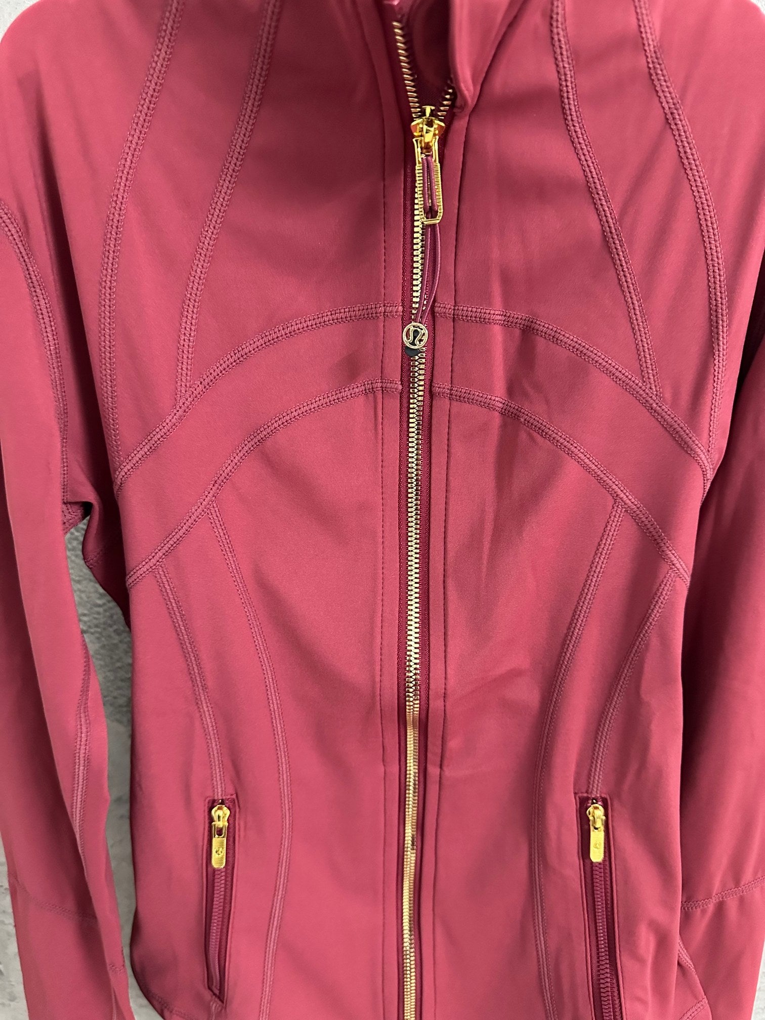Burgundy jacket front with gold center zipper and contrast topstitching seams