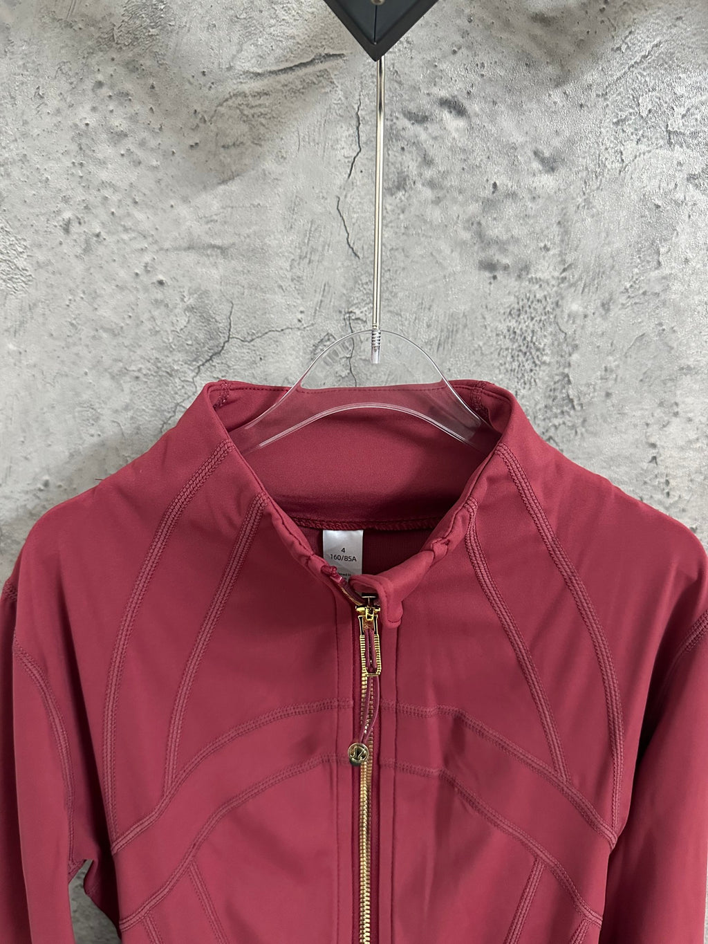 Burgundy zip-front jacket close-up with stand collar and gold zipper pull