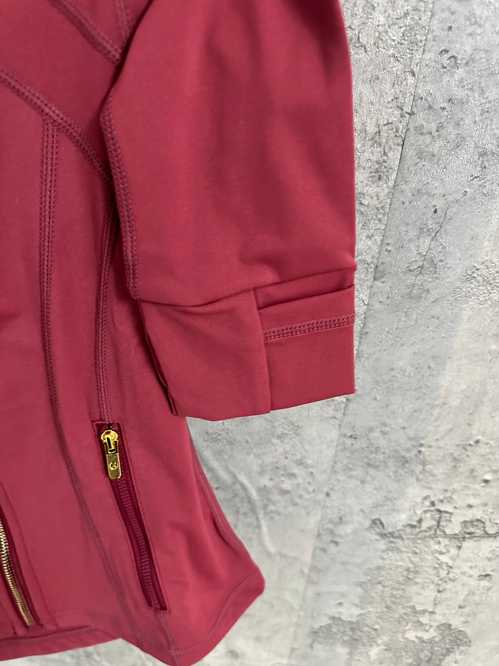 Burgundy jacket sleeve and hem detail with zip pocket and elastic cuff