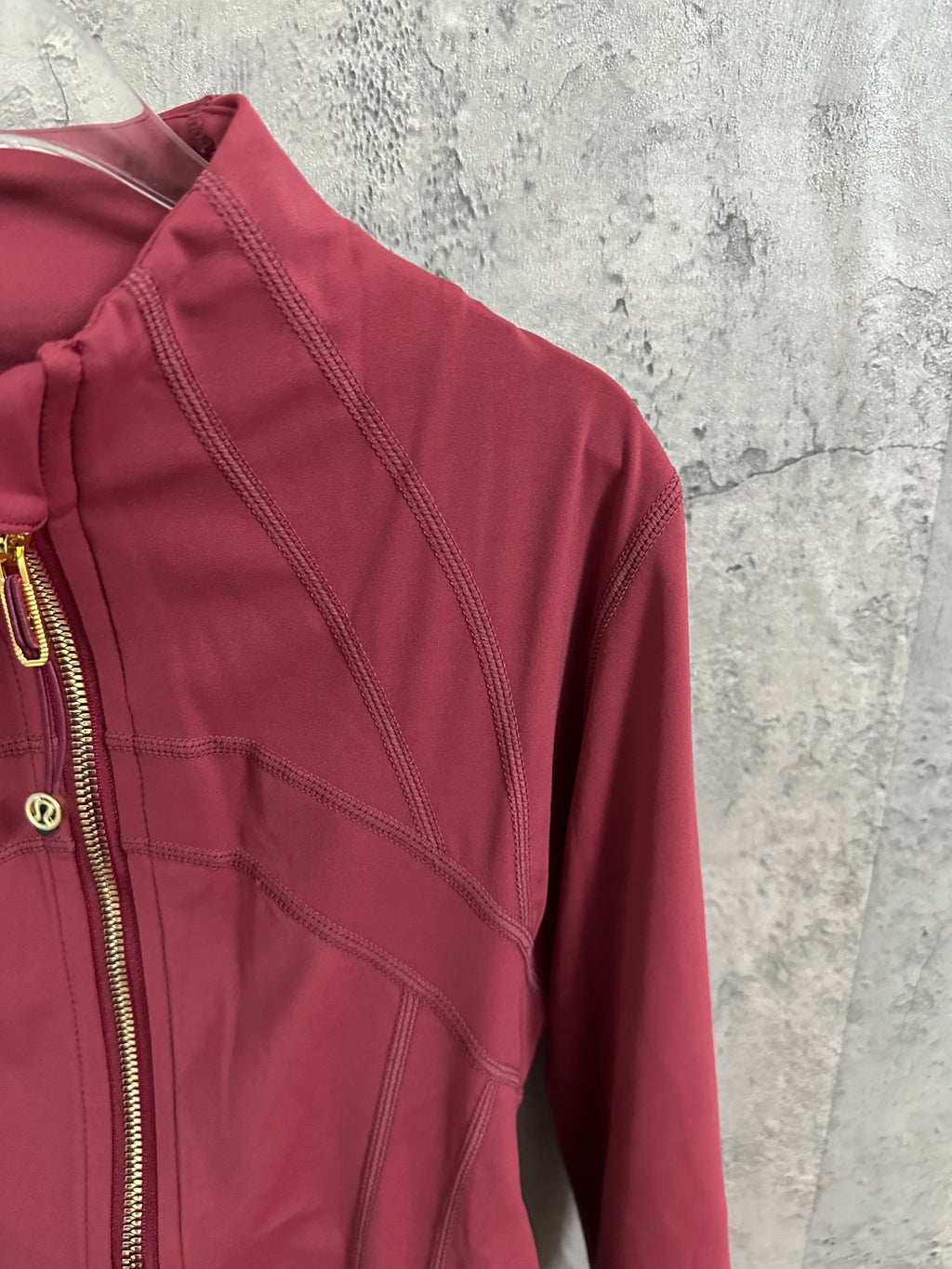 Burgundy jacket shoulder and sleeve close-up with seam stitching