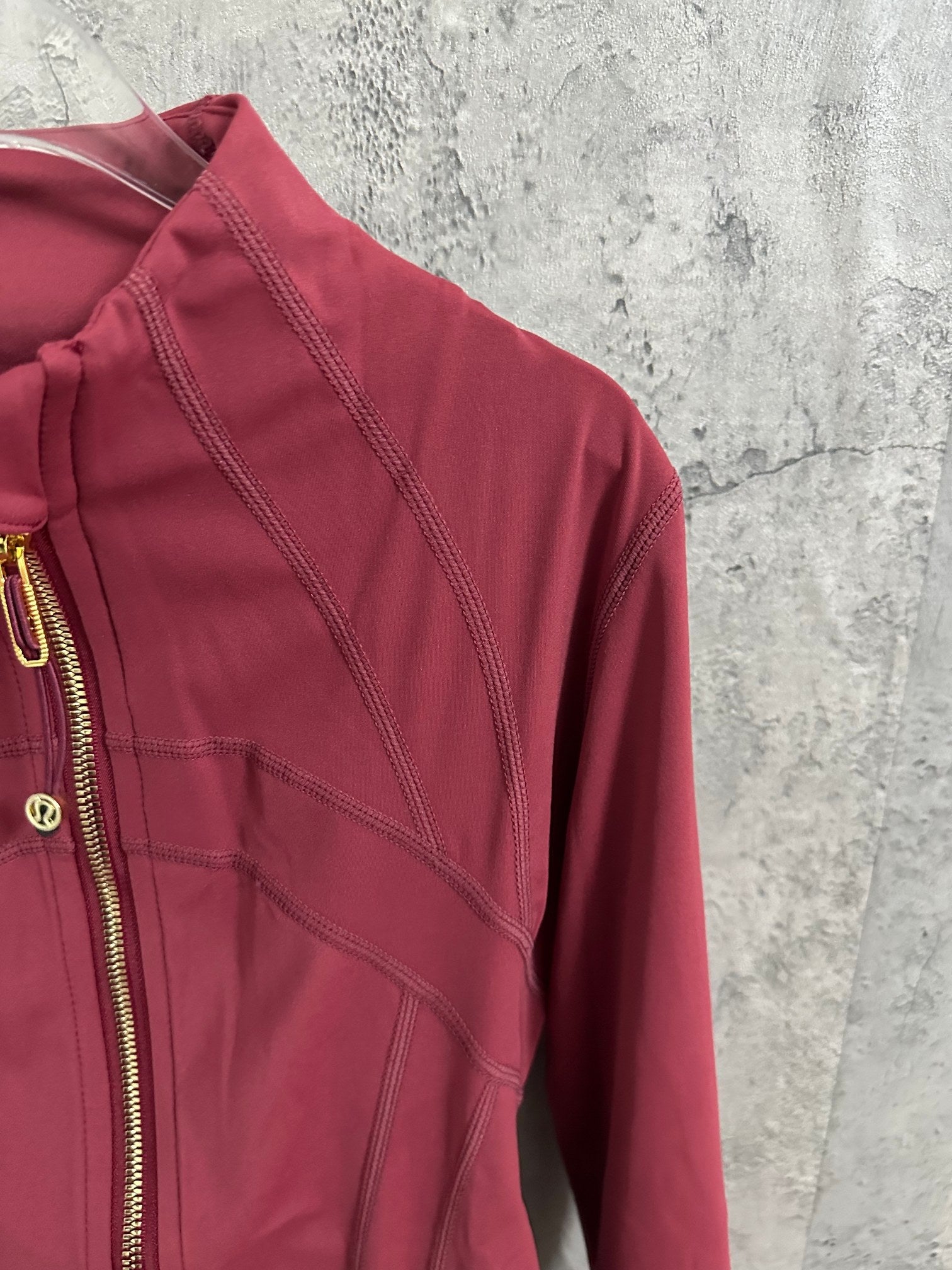 Burgundy jacket shoulder and sleeve with stitched panel lines