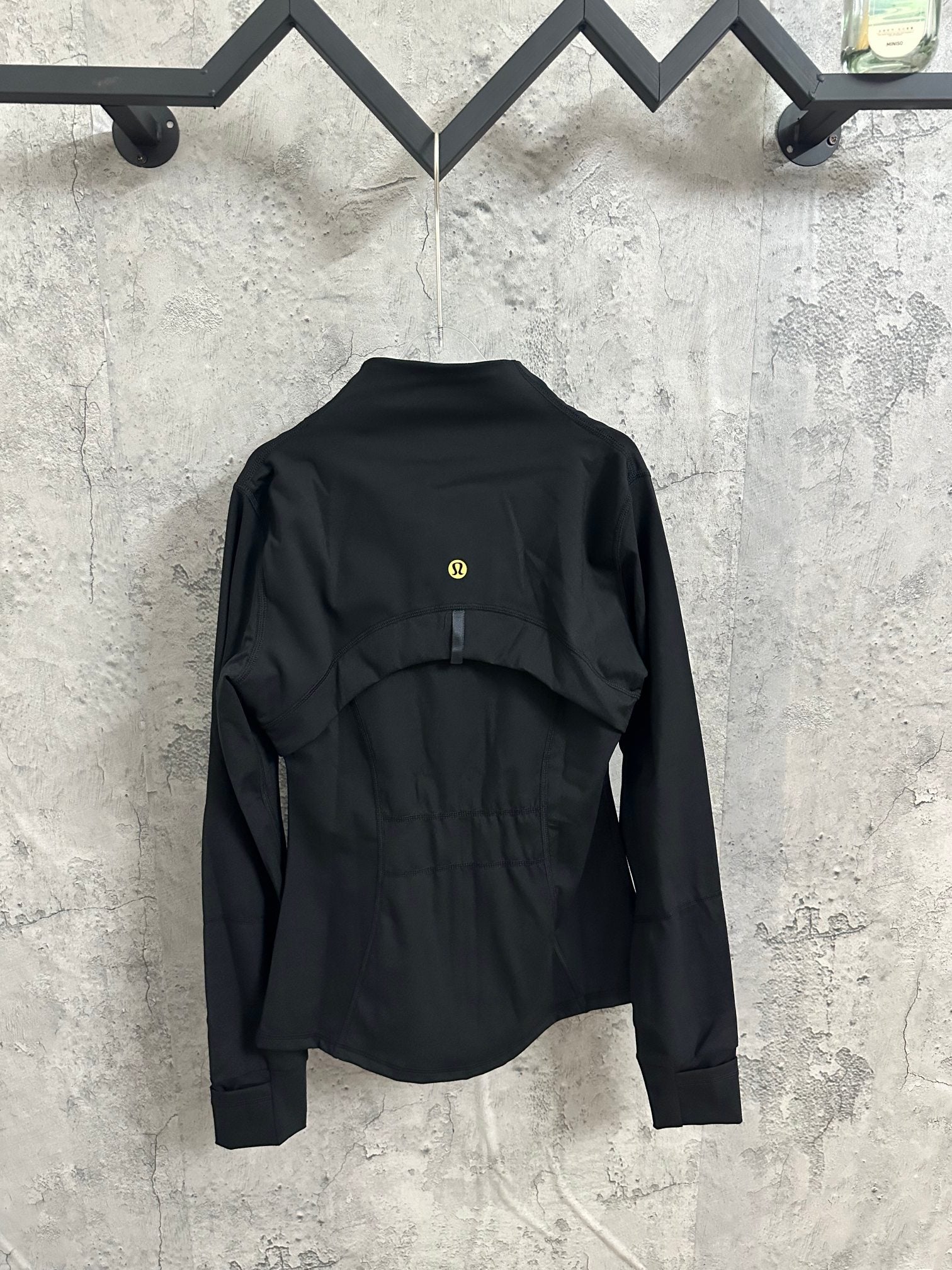 Black back-view bomber jacket with high collar and small gold emblem