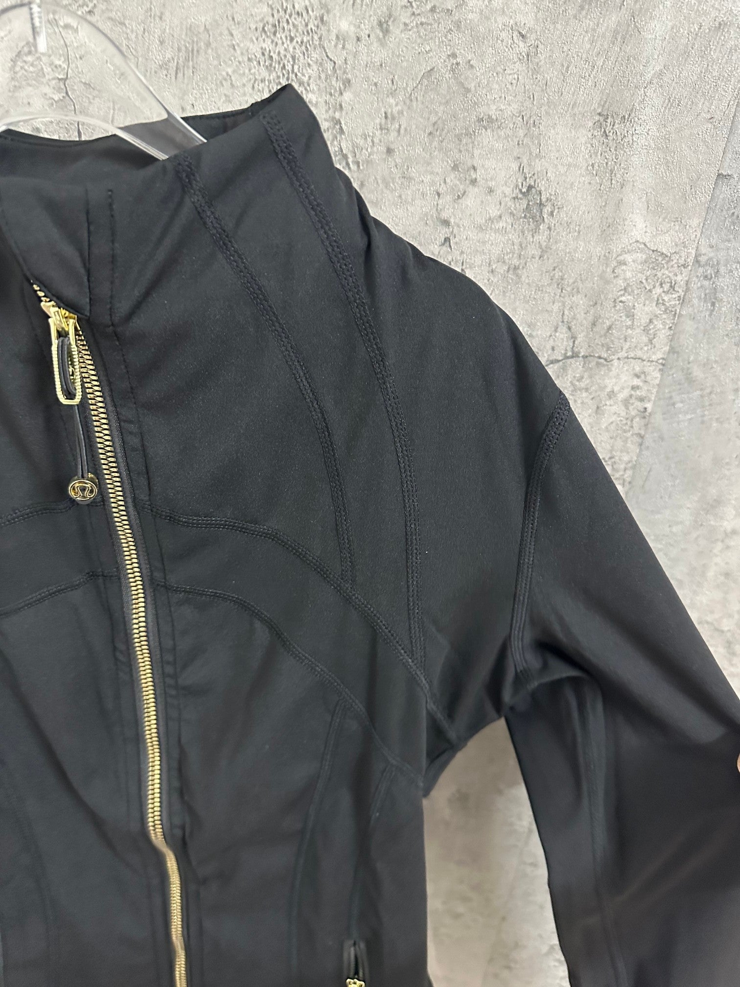 Black jacket front with gold-tone zippers along the panel