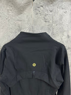 Black jacket back with round yellow emblem and draped yoke panel