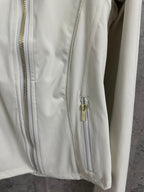 Light white zip-up jacket detail: front zipper with gold hardware and stitched vertical panels.